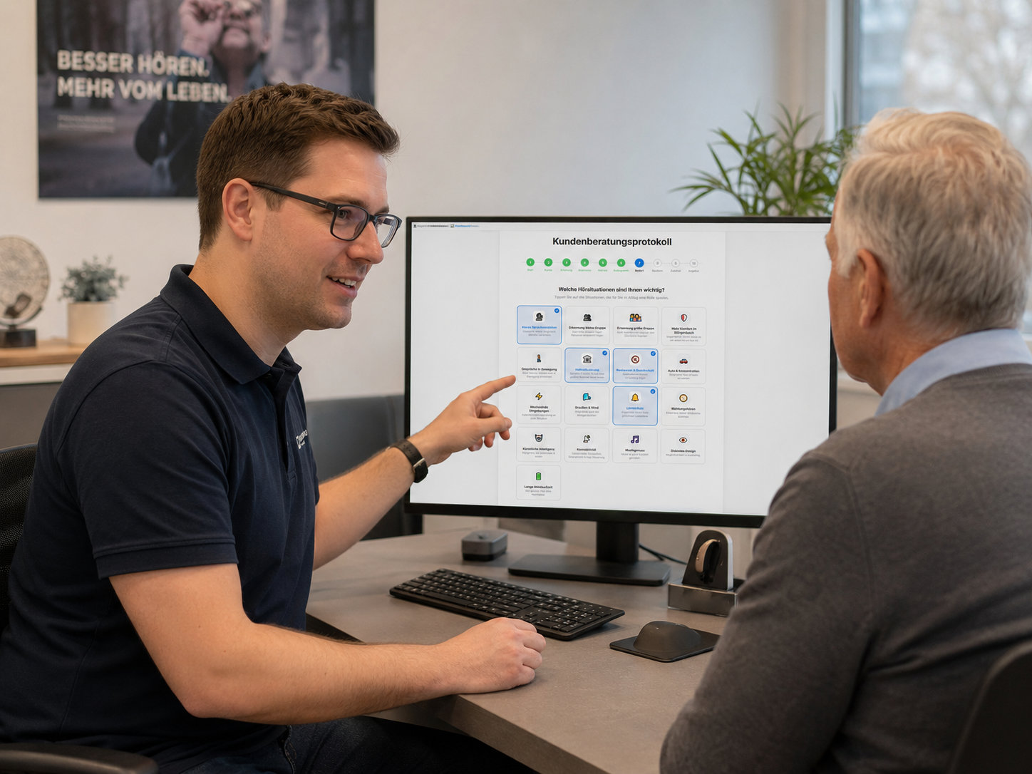 Hörakustiker berät einen Kunden am Monitor mit AnamOhre